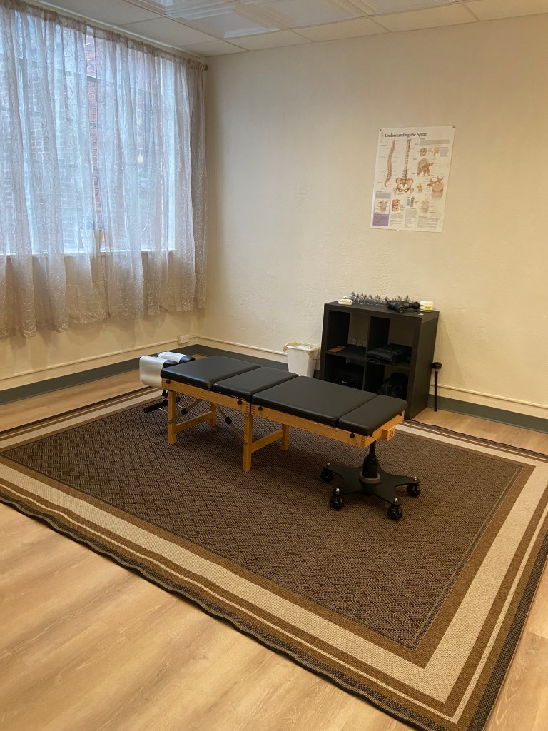 Empty therapy room with treatment table-- chiropractic adjusting table